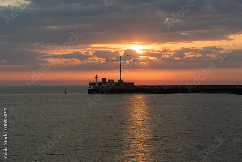 Sunset under a cloudy sky with a view of the entrance to the port of Le Havre.