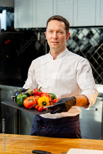 chef holding a tray with different washed vegetables ready use colorful vegetables in the kitchen