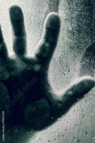 Mans figure with hands pressed against frosted glass. Shadow of a man behind the matte glass blurry hand and body soft focus. © andyborodaty