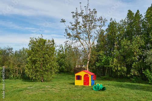 Charming countryside scene with little and vibrant plastic swing set and quaint cottage amidst lush fields