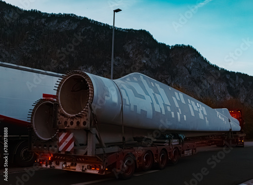Giant wind power plant rotor blade on a transporter at sunrise