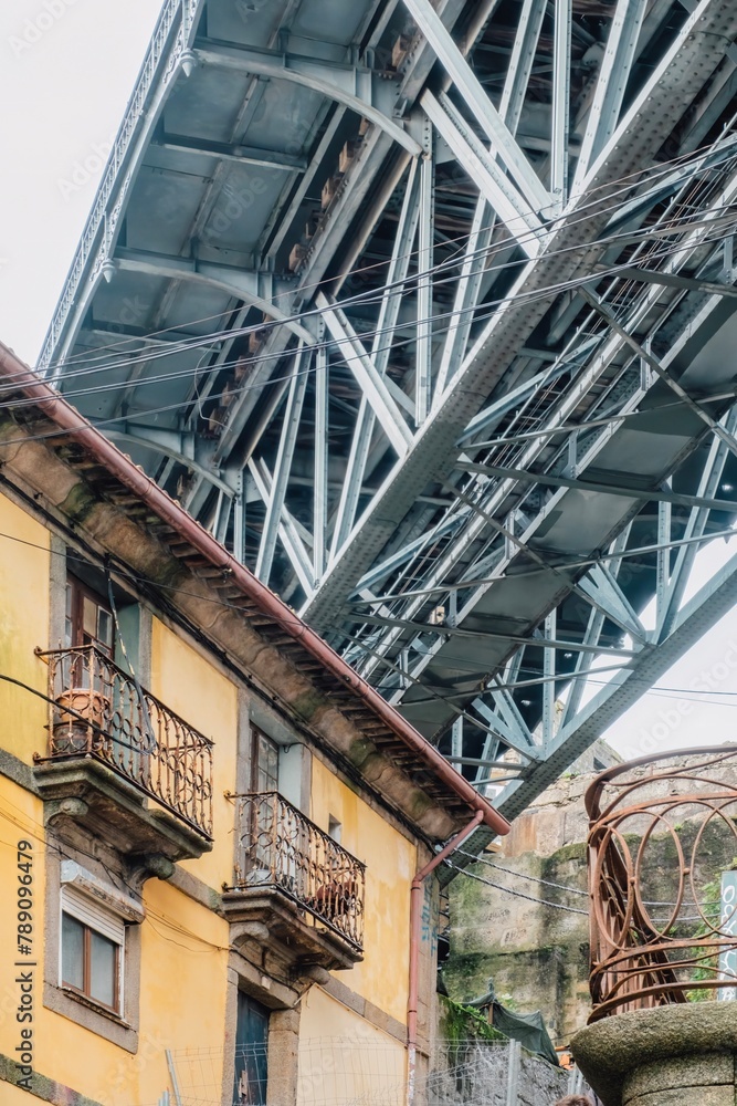 Obraz premium Street view of the narrow cobblestone streets of Porto with its old buildings and the Dom Luís I Bridge. Fragment of a metal railroad bridge, Portugal.
