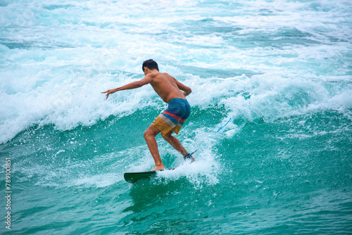 Surfing on a water board. A professional surfer rides the waves in Bali, Indonesia. Male athlete catches waves in the ocean.