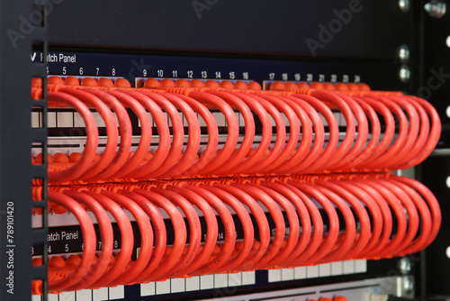 An Ethernet Internet signal switch with patch cords connected to patch panels in a telecommunications rack. Soft focus.