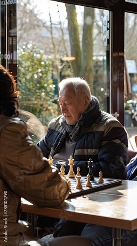 Elderly man playing chess with a fellow resident in a sunny lounge