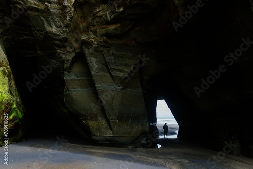 Lone person walking through a hle in the rock at the Three Sisters, Tongaporutu, Taranaki, New Zealand. photo