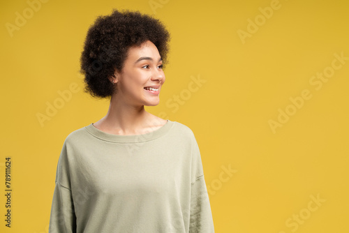 Happy African American woman posing in studio over yellow background with copy space