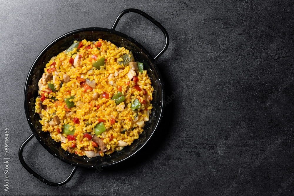 Yellow rice with chicken and vegetables on black slate background. Top view. Copy space - obrazy, fototapety, plakaty 