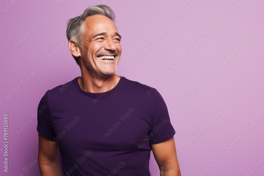 Portrait of a grinning man in his 50s donning a trendy cropped top on solid color backdrop Portrait of a grinning man in his 50s donning a trendy cropped top on solid color backdrop