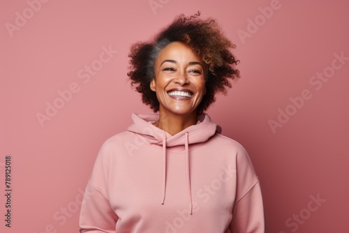 Portrait of a grinning afro-american woman in her 60s wearing a thermal fleece pullover over solid color backdrop