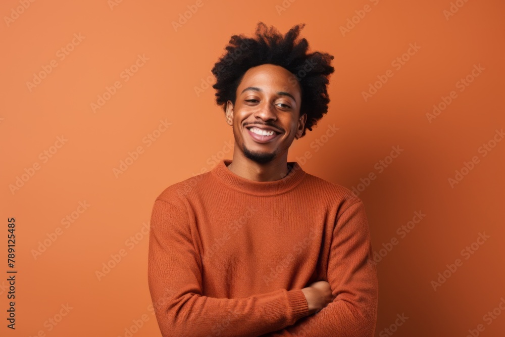 Obraz premium Portrait of a satisfied afro-american man in his 20s wearing a cozy sweater on solid color backdrop