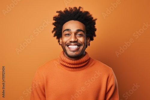 Portrait of a satisfied afro-american man in his 20s wearing a cozy sweater in solid color backdrop © Markus Schröder