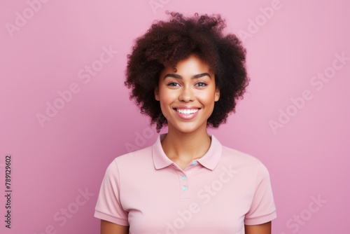 Portrait of a blissful afro-american woman in her 20s wearing a sporty polo shirt over solid pastel color wall