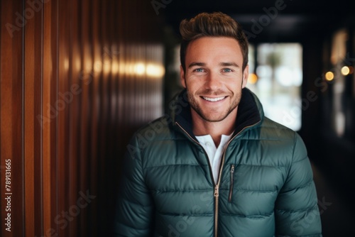Portrait of a smiling man in his 30s sporting a quilted insulated jacket over scandinavian-style interior background