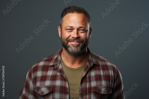 Portrait of a satisfied man in his 40s wearing a comfy flannel shirt isolated on blank studio backdrop