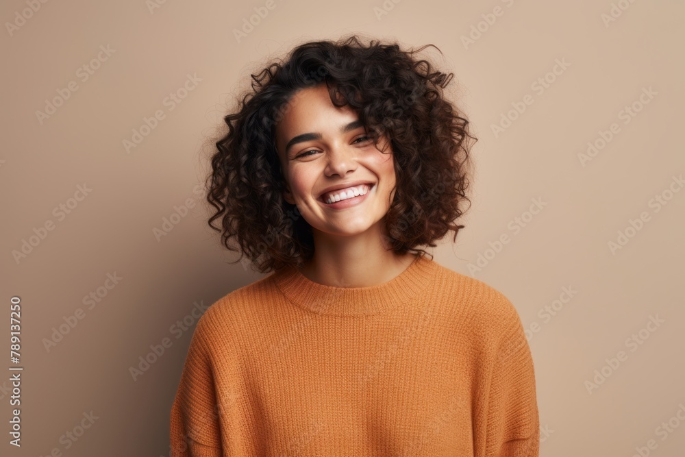 Portrait of a happy woman in her 20s dressed in a warm wool sweater in front of blank studio backdrop Portrait of a happy woman in her 20s dressed in a warm wool sweater in front of blank studio backdrop