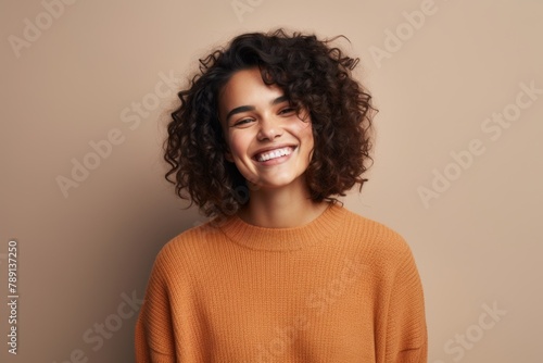 Portrait of a happy woman in her 20s dressed in a warm wool sweater in front of blank studio backdrop