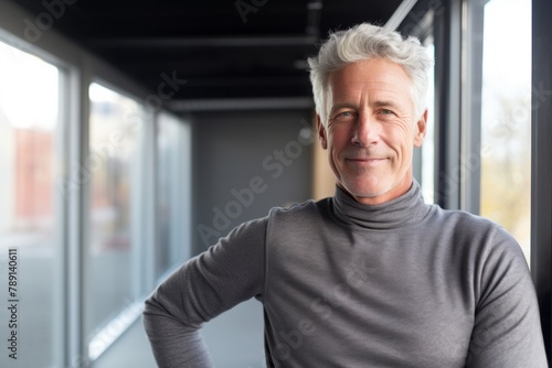 Portrait of a blissful man in his 60s showing off a thermal merino wool top in front of empty modern loft background