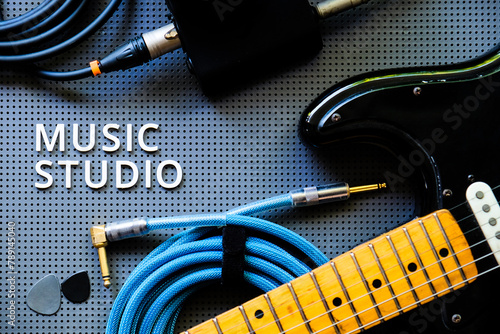 Electric guitar, Instuments and cable on a gray background with the word Music Studio. Music concept