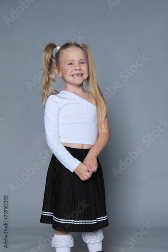 Little girl stands confidently, her bright smile and playful pigtails echoing her vibrant personality and stylish outfit.