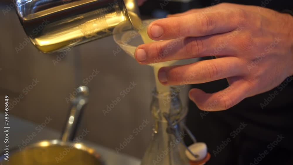 Close up side view 4k shot on bartender's hands pouring lemon juice in a bottle through a plastic funnel Close up side view 4k shot on bartender's hands pouring lemon juice in a bottle through a plastic funnel