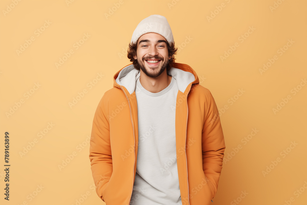 A young man with a bright, engaging smile, dressed in a vibrant orange jacket and white hoodie, exudes warmth and joy against a peach background. A young man with a bright, engaging smile, dressed in a vibrant orange jacket and white hoodie, exudes warmth and joy against a peach background.