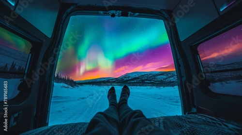 View from inside of a vintage camper van in wild snow field with beautiful aurora northern lights in night sky with snow forest in winter.