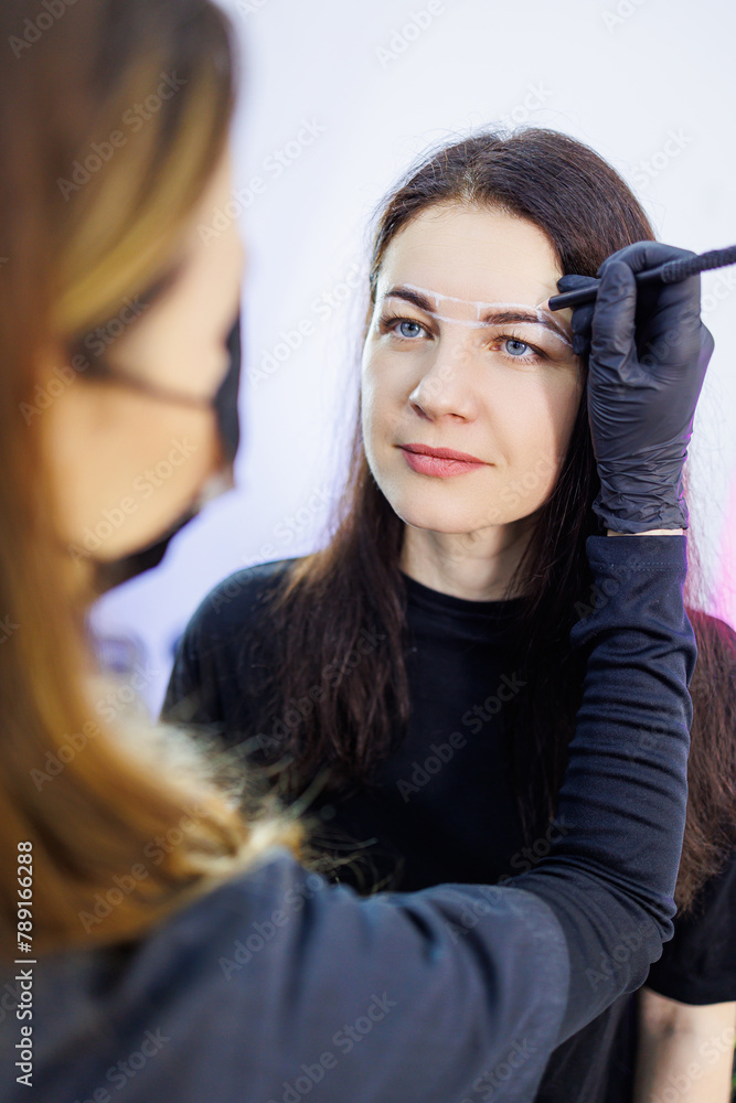 The master marks a woman's face before permanent eyebrow makeup. Eyebrow tattoo. Cosmetic procedure for a woman's face The master marks a woman's face before permanent eyebrow makeup. Eyebrow tattoo. Cosmetic procedure for a woman's face
