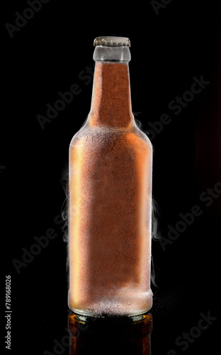Beer bottle with frost and water vapor on black background..