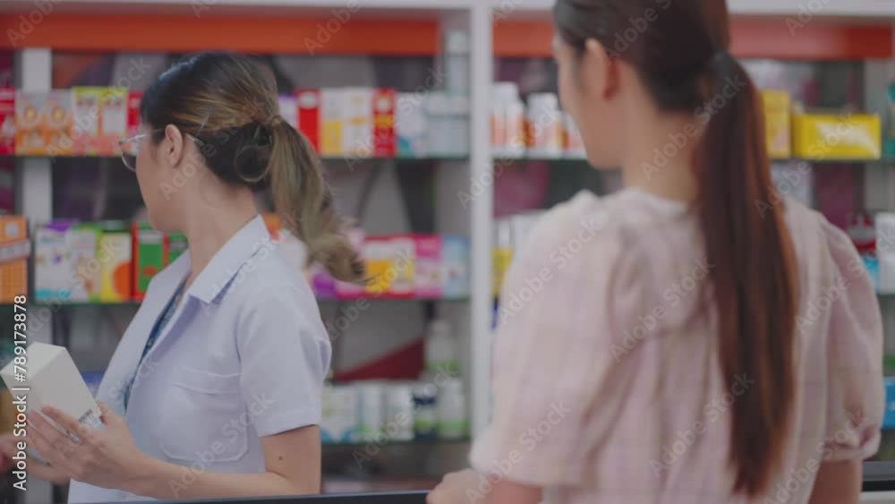An Asian pharmacist explains medication details to a focused client against a backdrop of pharmacy shelves, Slow Motion An Asian pharmacist explains medication details to a focused client against a backdrop of pharmacy shelves, Slow Motion