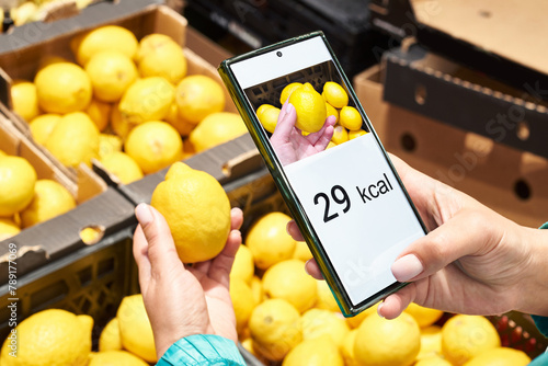 Checking calories on lemon in store with smartphone