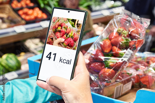 Checking calories on strawberry in store with smartphone © Sergey Ryzhov