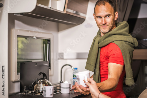 Man Serving Hot Drinks While Standing Next to Camper Van Kitchen