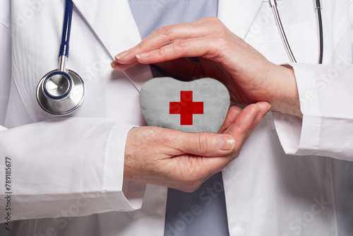 Doctor holding heart with Red cross symbol on white background. Healthcare, charity, insurance and medicine concept