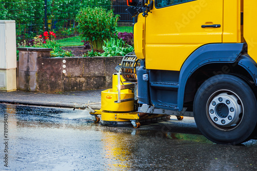 Removing oil spills. Yellow Truck remove engine oil from a street. oil spilling on the road in a residential district. Oil Spill Clean Up by vehicle. close-up of front of truck