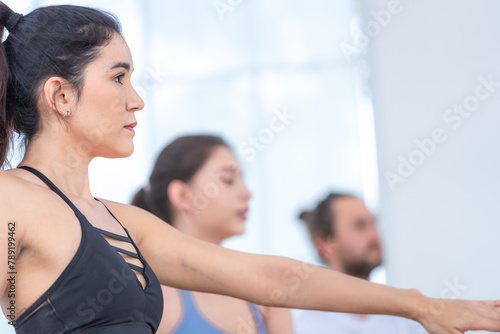 Confident yoga participant performs a balance-focused pose during a class, exuding strength and determination.