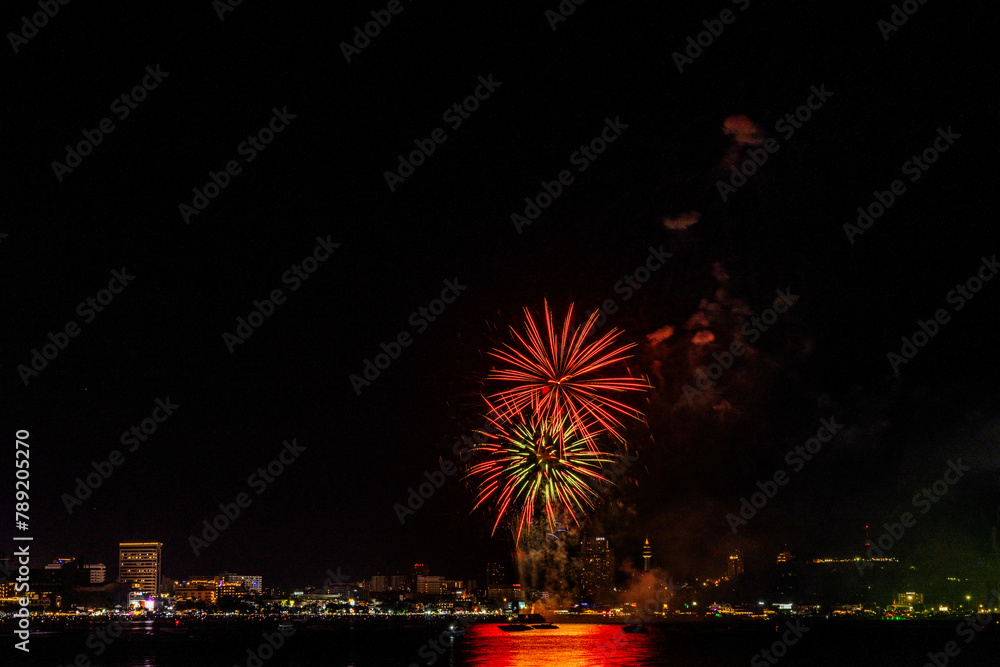 Mesmerizing display of fireworks explodes in the night, illuminating the waterfront with a tapestry of light.