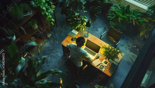 An overhead view of an office focuses on one person sitting at their desk in deep thought about joy and love, symbolizing personal growth through emotional intelligence. The room is well lit but dar