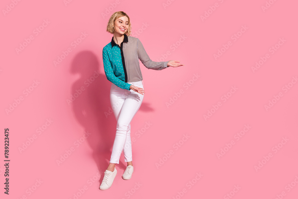 Full size photo of pretty young girl hands hold empty space wear trendy striped cyan outfit isolated on pink color background Full size photo of pretty young girl hands hold empty space wear trendy striped cyan outfit isolated on pink color background