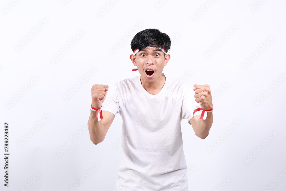 Wow surprised asian young boy with red white ribbon for celebrating Indonesia independence day standing while shouting with fist hands Wow surprised asian young boy with red white ribbon for celebrating Indonesia independence day standing while shouting with fist hands