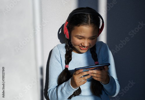 Girl with headphones having fun while using smartphone photo