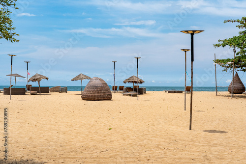 Empty sandy beach with yellow sand in sunny weather on which there are sun umbrellas and sun loungers and beach furniture.	