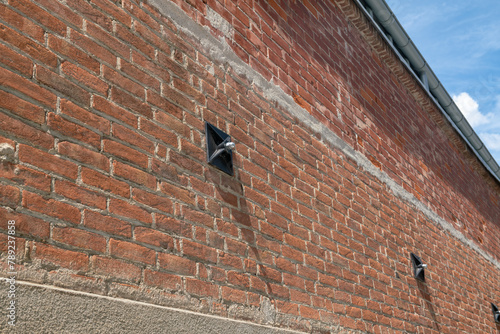 Tie rod on the wall of an exposed brick building with construction detail of the keys supporting the internal tie rods, key - counterthrust chain for a renovated building.