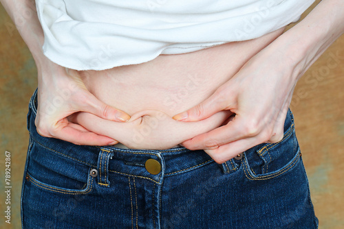 Bloated woman holding belly fat on her stomach