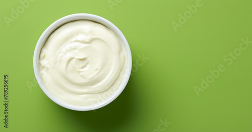 Top view of bowl with white quark or cream on side of green background with copy space сreated with Generative Ai