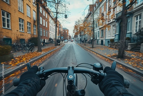 A forward-looking view of a cyclist riding on a lonely road covered with fallen autumn leaves and urban residential architecture photo