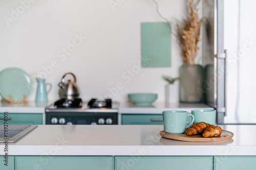 cup of coffee and fresh croissants on wooden tray on dining table at kitchen © brizmaker
