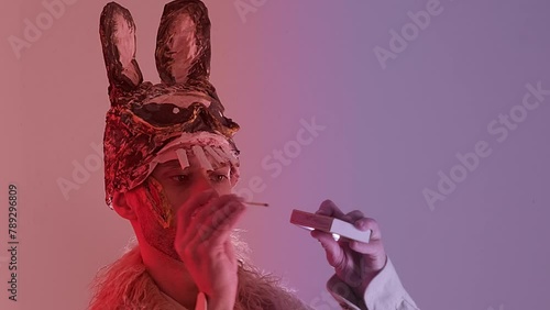 scary maniac man, young guy in cringe in scary bunny mask lights match, looks at fire, pyromania concept, theme of fear and horror, concept run while match burns, Halloween and Festive Costumes