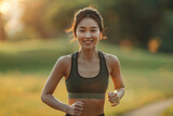 Active young Asian woman jogging in a park at sunset wearing sportswear