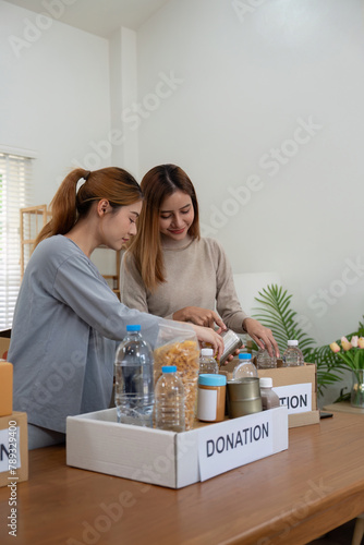 Donation and two woman volunteer asian of happy packing food in box at home. Charity